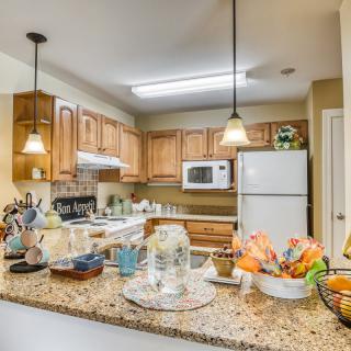 A cozy kitchen with wooden cabinets, granite countertops, and various appliances.
