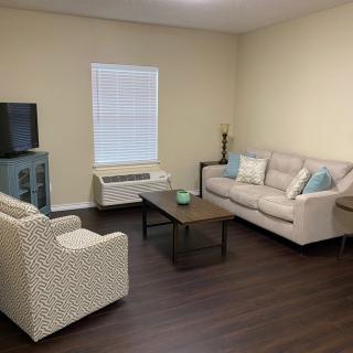 A cozy living room with a sofa, armchair, coffee table, and a TV.