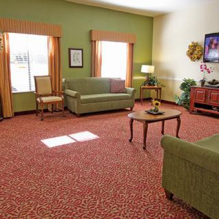 A cozy living room with green sofas, a coffee table, and warm decor.