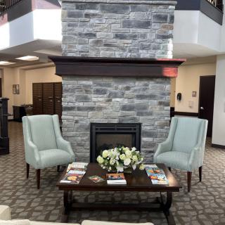 A cozy lobby seating area with a fireplace and two armchairs.