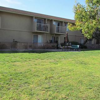 A residential building with balconies overlooking a grassy area and trees.