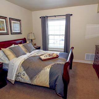 A cozy bedroom with a neatly made bed, decorative pillows, and soft lighting.