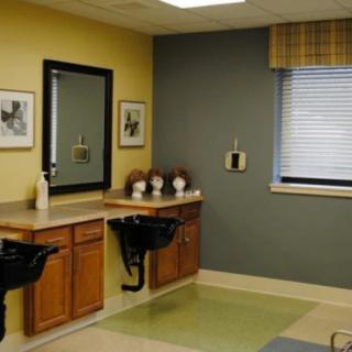 Interior of a small hair salon with counters and wigs on display.