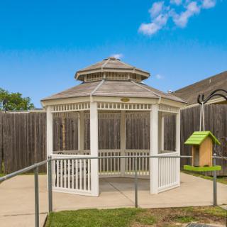 A white gazebo surrounded by lush green grass, perfect for relaxation in an outdoor space.