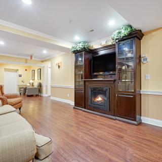 A cozy living room with a fireplace and TV cabinet, featuring hardwood floors and comfortable seating.