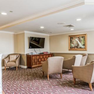 A cozy lounge area with comfortable chairs, a television, and decorative artwork on the walls.