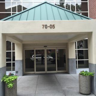 The entrance of a modern building featuring a distinctive roof and planters.