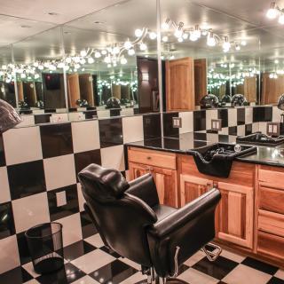 A stylish barbershop interior featuring black and white checkered tiles, mirrors, and a classic barber chair.