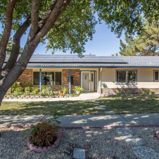 A suburban house with a well-maintained front yard and a large tree providing shade.