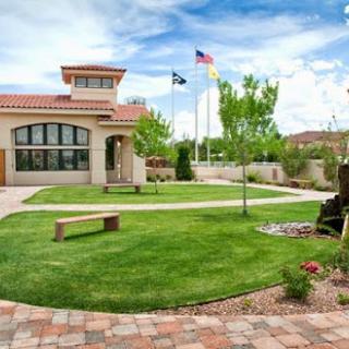 A serene outdoor space featuring a well-maintained lawn and a modern building with flags.