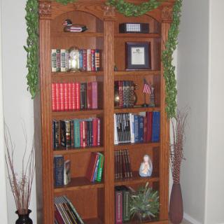 A beautifully arranged wooden bookshelf adorned with decorative plants and a variety of books.