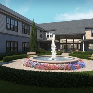 A beautifully landscaped courtyard featuring a central fountain surrounded by colorful flowers and well-maintained greenery.