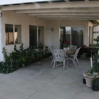 A cozy outdoor patio with a dining set and potted plants under a covered area.