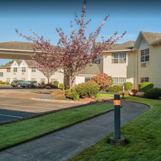 A view of a building with a landscaped garden and parking lot in the foreground.