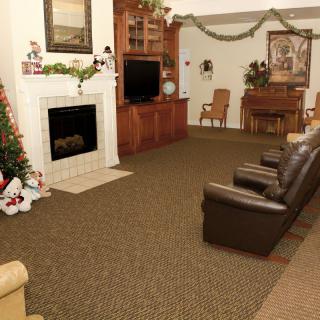 A cozy living room decorated for the holidays with a fireplace, television, and Christmas decorations.