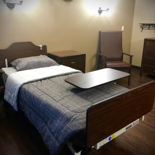 A hospital room featuring a single bed with medical accessories and furniture.