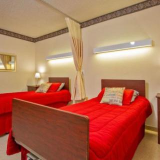 A modern bedroom with twin beds featuring red bedding and soft lighting.