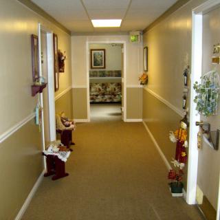 A well-lit hallway with decorative items and wall art leading to a seating area.