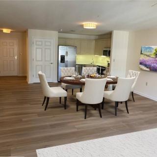 A modern dining area with a round table and upholstered chairs, featuring an open kitchen layout and wooden flooring.