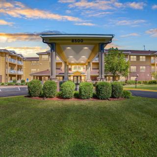 A modern hotel building with a well-maintained lawn and clear blue sky.
