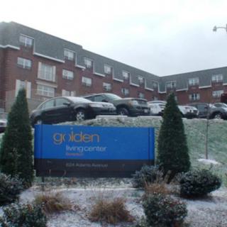 A snowy day at a residential building with cars parked outside.