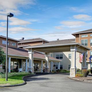 Entrance of a residential building with a driveway and landscaped surroundings.