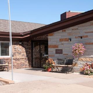 The entrance of a well-maintained building featuring stonework and beautiful floral arrangements.