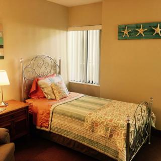 A cozy bedroom with a single bed, decorated with soft colors and starfish wall art.