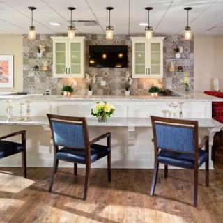 Modern kitchen interior with a large countertop, chairs, and pendant lighting.
