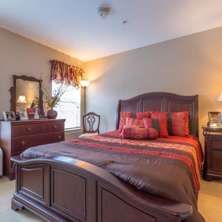 A cozy, traditional-style bedroom with wooden furniture and warm lighting.