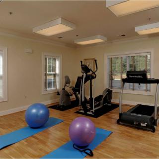 A compact home gym setup featuring various exercise equipment including yoga mats, exercise balls, a treadmill, and an elliptical machine.