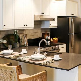 A modern kitchen featuring a stylish island with dining setup, complemented by white cabinets and stainless steel appliances.