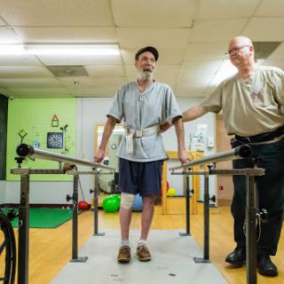 A patient receiving physical therapy assistance while practicing walking with the help of a therapist.