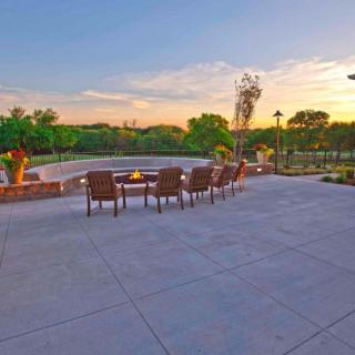 A spacious patio with chairs overlooking a picturesque sunset and lush landscape.