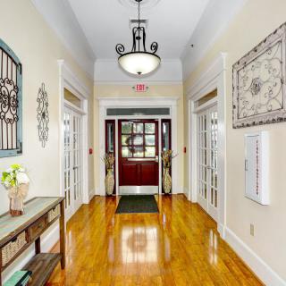 A beautifully decorated hallway with polished wood floors, a chandelier, and double doors at the end.