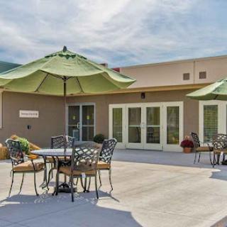 A serene outdoor patio area featuring tables, chairs, and green umbrellas, perfect for relaxation.
