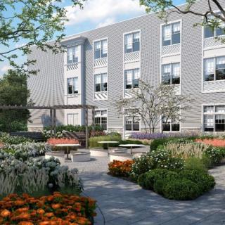 A modern building with a beautifully landscaped courtyard featuring flowers and seating areas.