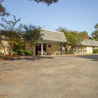 A building with a parking lot and trees under a clear sky.