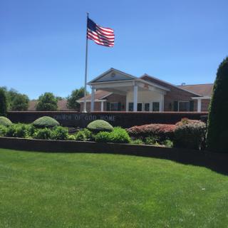 A well-maintained building with a lush green lawn and a prominent American flag waving in the breeze.