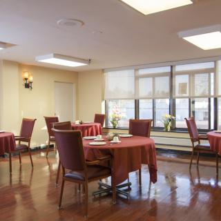 An elegant dining area with neatly arranged tables and chairs, featuring large windows that bring in natural light.