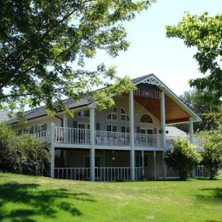 A beautiful house surrounded by lush greenery and sunlight.