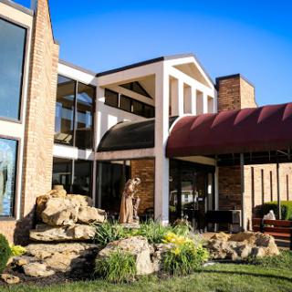 A modern architectural building featuring a combination of glass and brick elements, complemented by landscaped surroundings.