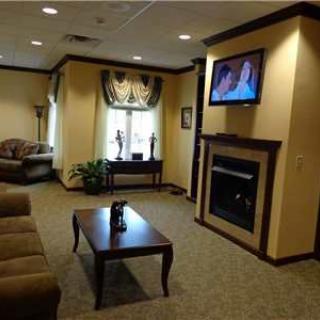 A cozy waiting room with comfortable seating, a television, and a fireplace.