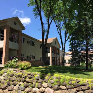 A serene residential building surrounded by trees and lush greenery.