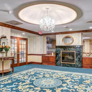 A luxurious lobby with a chandelier, fireplace, and ornate rug.