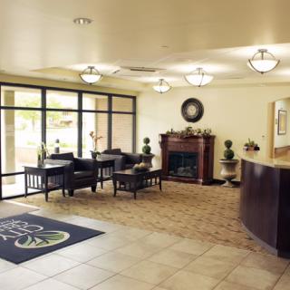 A spacious and well-lit lobby with a reception desk, seating area, and fireplace.