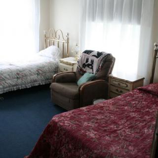 A cozy bedroom with two beds and an armchair by the window.