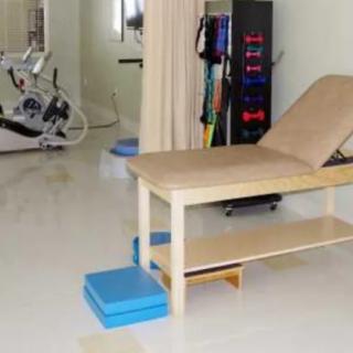 A physical therapy room with a treatment table and exercise equipment.