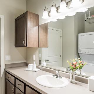A well-lit modern bathroom featuring a sink, cabinets, and a laundry area.