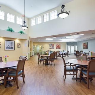 A spacious dining area with tables and chairs, featuring high ceilings and decorative lighting.